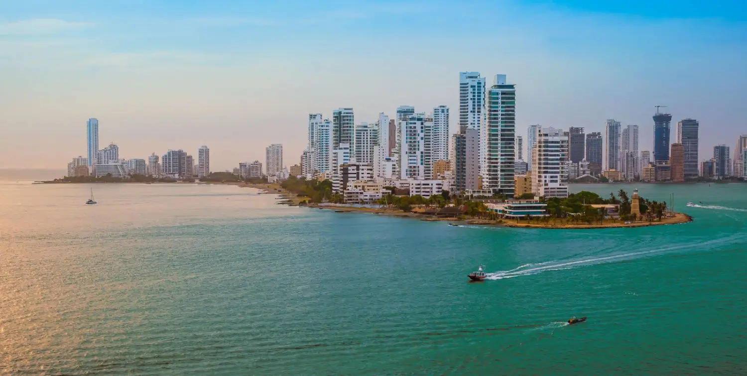 Panoramic view of an urban cityscape in Colombia, featuring boats on the sea, amidst natural outdoor scenery.
