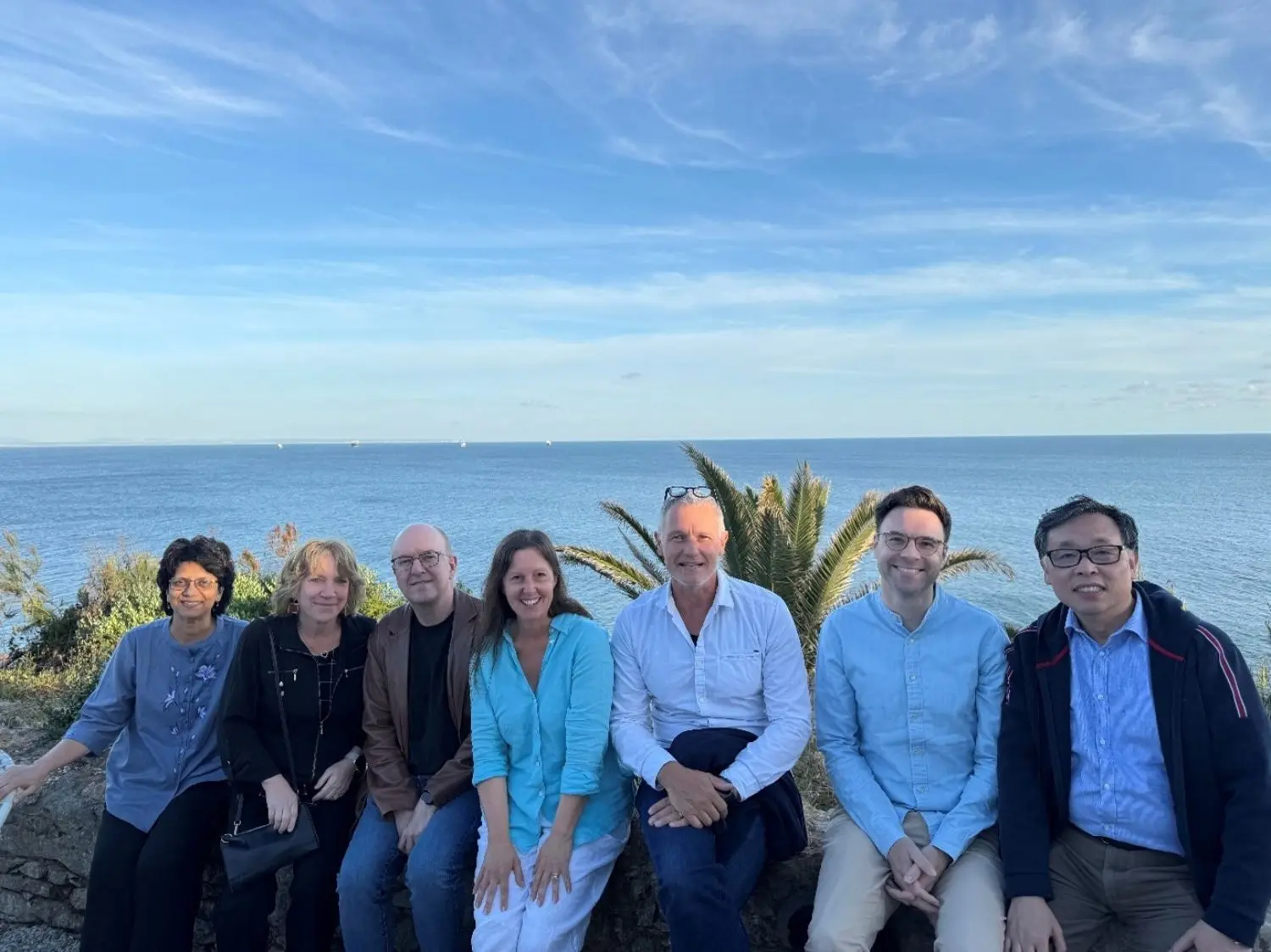 Group photo of multiple people sitting with an ocean view