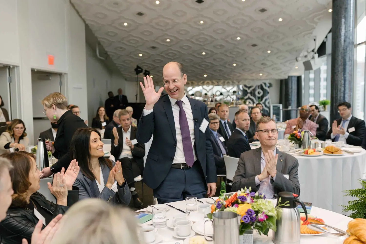 Photo from 37th annual Canadian Insurance Outlook Breakfast: man standing and people applauding.